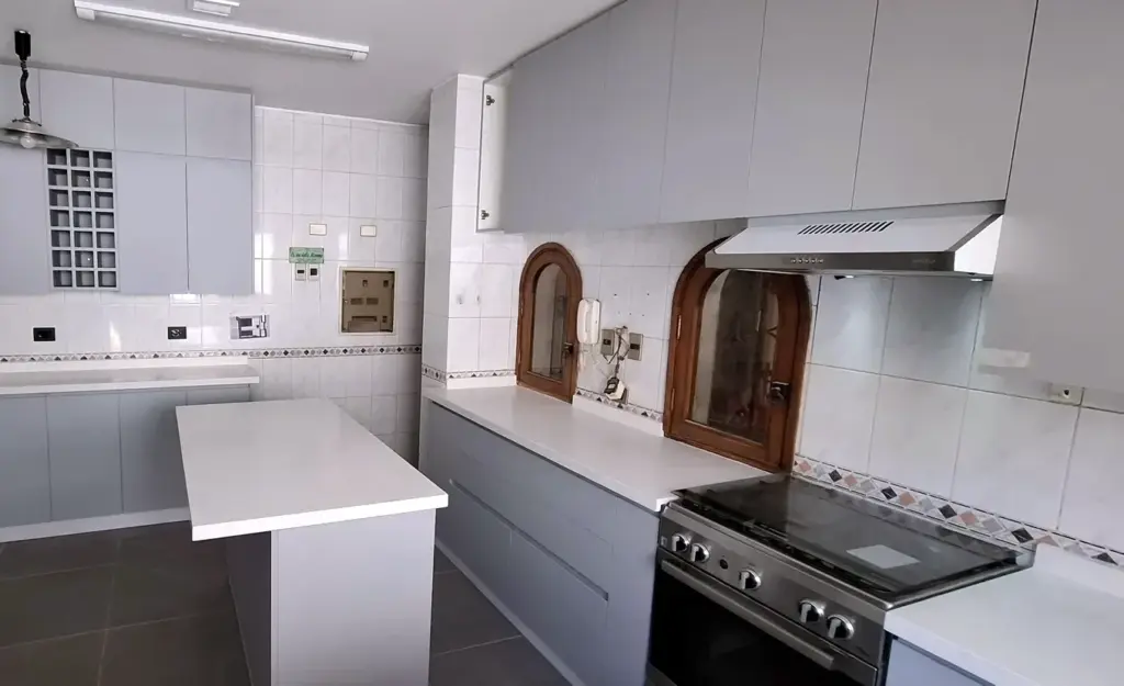 Cocina blanca con zócalo de madera en Vitacura, sin el refrigerador